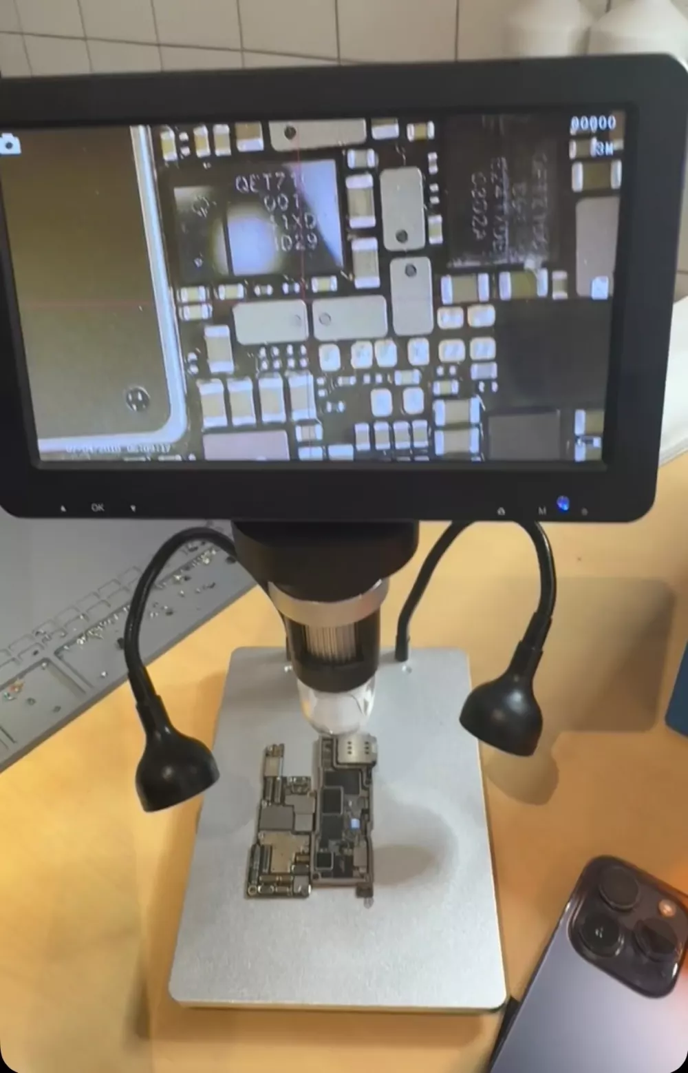 Microscope numérique au-dessus d'une carte mère d'iPhone pendant une micro-soudure